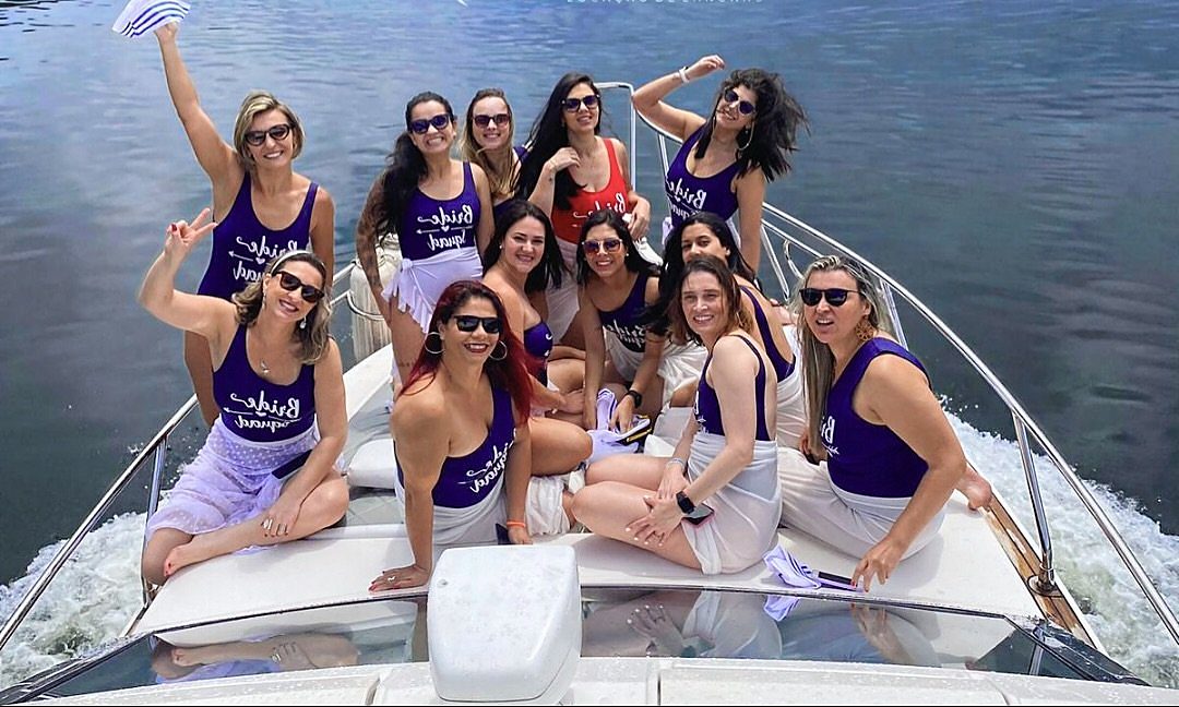 Grupo de amigas com camisetas iguais na proa, em despedida de solteira